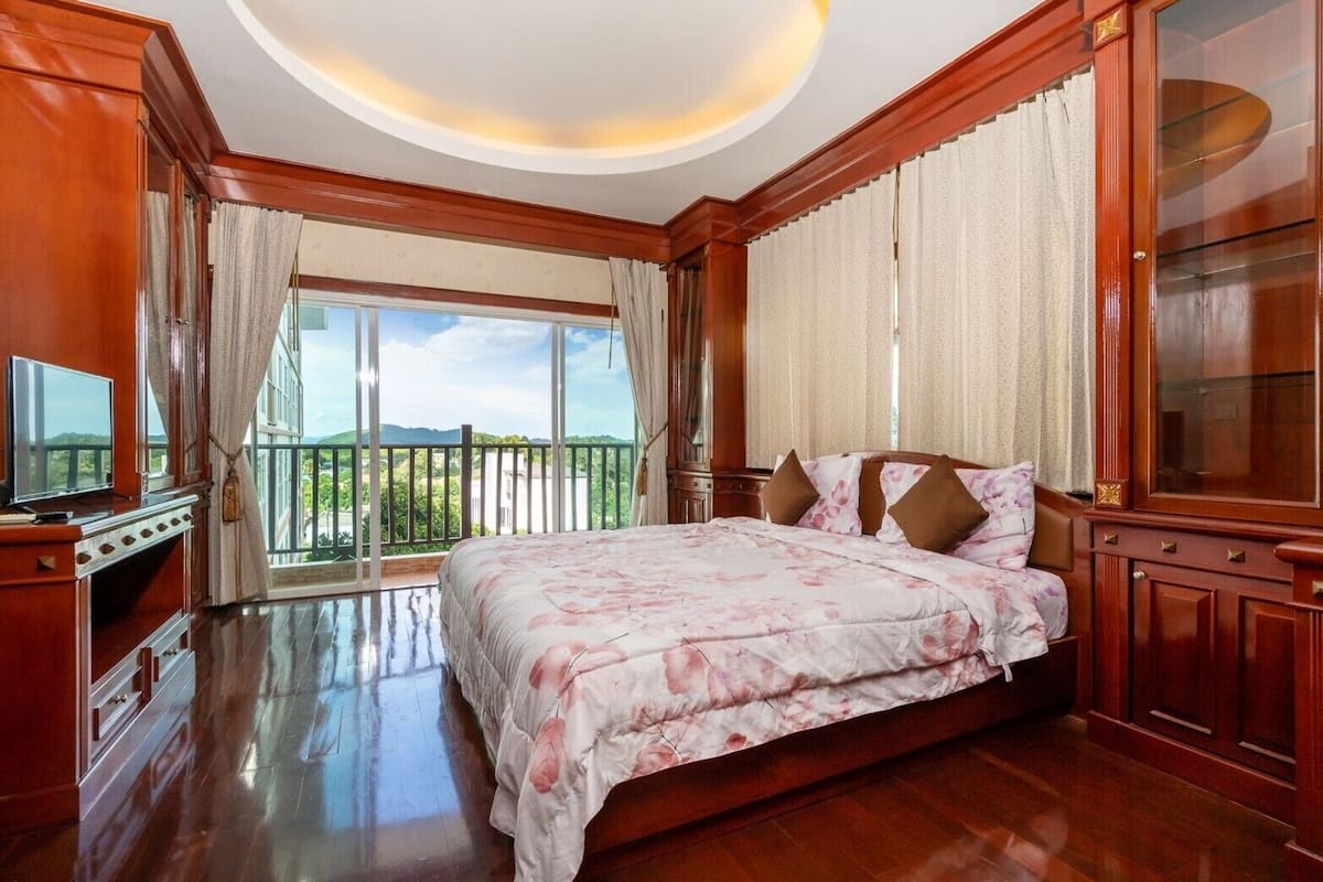 Un dormitorio con una cama grande, televisión y un balcón con vistas.