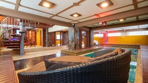A spacious indoor area with a central pool, a staircase, and a seating area. - Angel Pool Villa Phuket (Ratsada)