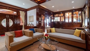 A spacious living room with a large sofa set, a glass coffee table, and wooden paneling. - Angel Pool Villa Phuket (Ratsada)