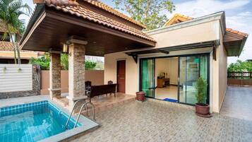 A modern house with a swimming pool, covered patio, and a glass door leading to an interior space.