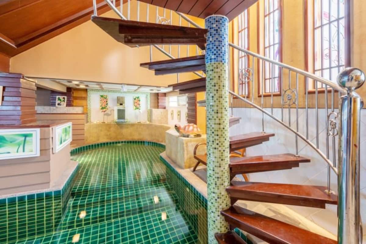 Una escalera de caracol con escalones de azulejos verdes que conducen a una zona en el segundo piso con una piscina.