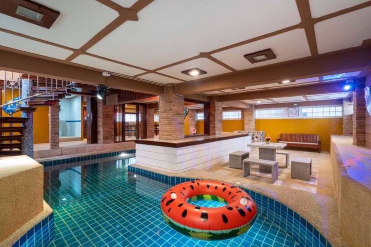 Una piscina interior con un aro hinchable rojo, una escalera y un área de descanso con un banco y una mesa.