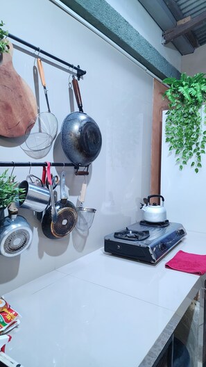 A kitchen with hanging pots and pans, a gas stove, and a hanging plant. - Semeru Hostel Malang - Adults Only (Malang)