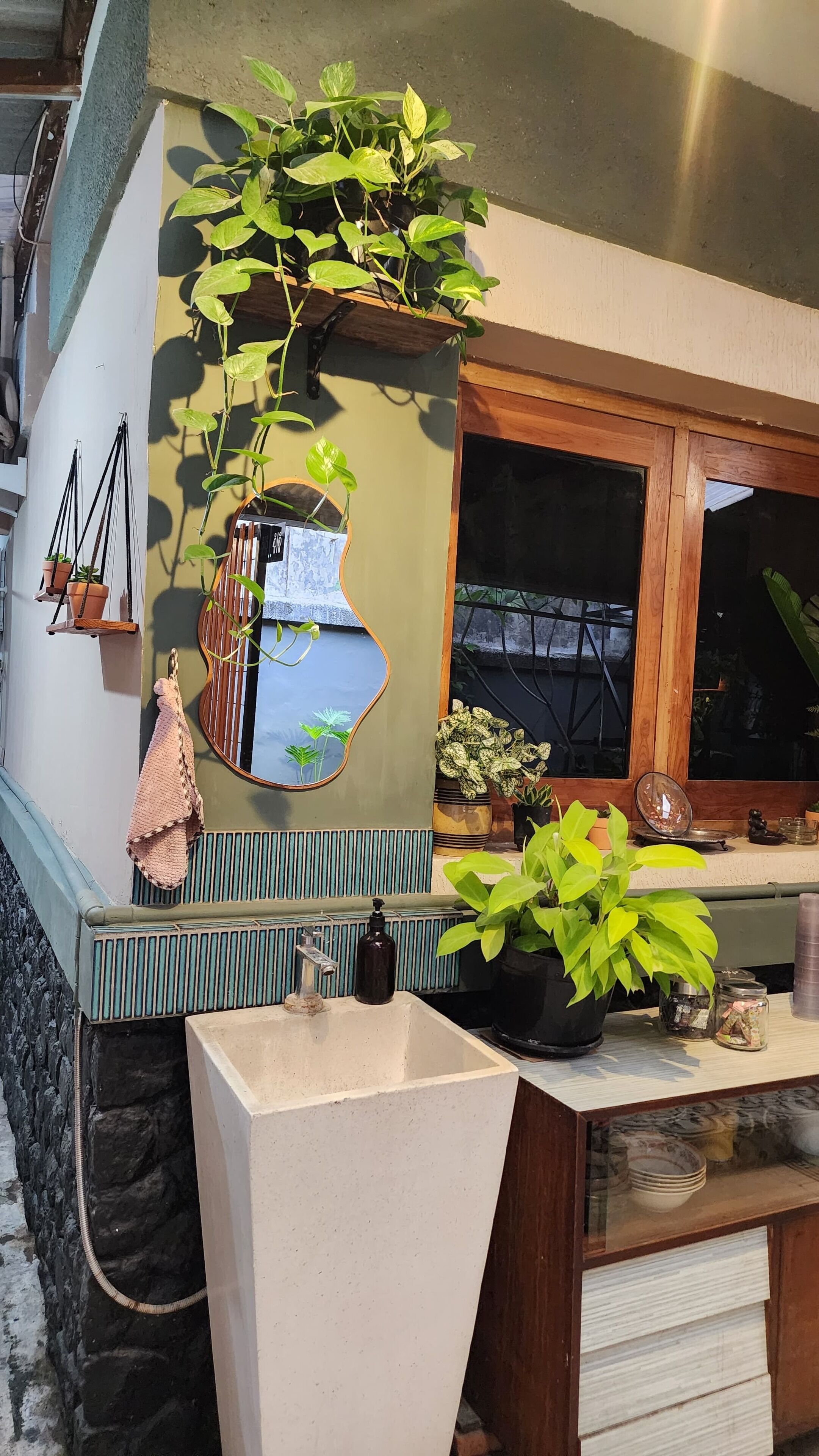 Un baño con lavamanos, espejo y plantas en macetas.