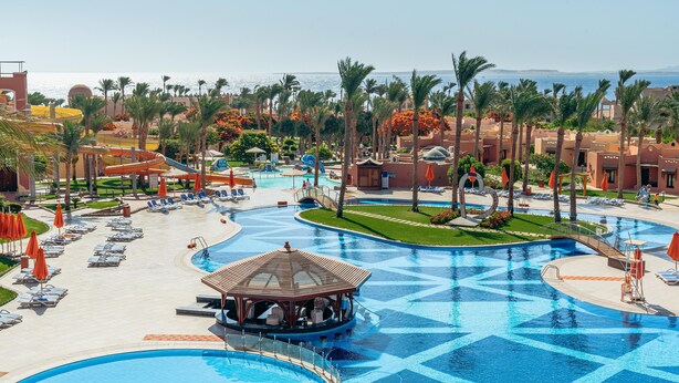 Un complexe hôtelier doté de plusieurs piscines, de palmiers et offrant une vue sur la plage.