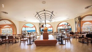 Un restaurant spacieux avec de hauts plafonds, de grandes fenêtres et un espace de sièges central.