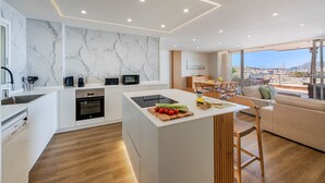 A modern kitchen with a marble backsplash, wooden flooring, and a large island with fresh produce.