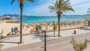 A beach with palm trees, a playground, and a clear blue sea.
