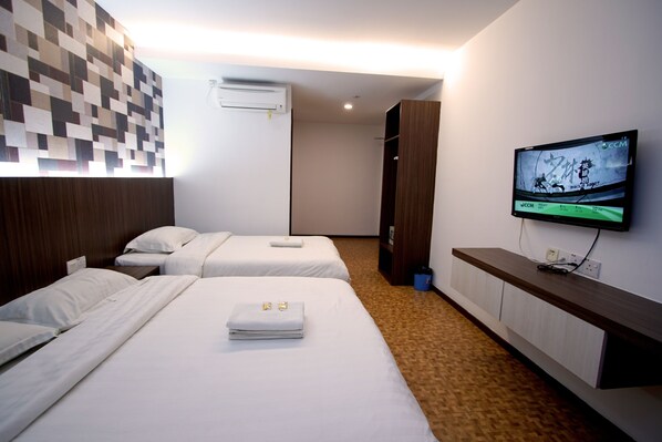 A hotel room with two beds, a flat-screen TV mounted on the wall, and a wooden headboard.