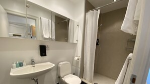 A modern bathroom with a white sink, toilet, and shower. - PSG 23 - Short Stay Apts by Living Suites (Copenhagen)
