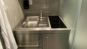 A compact kitchen with a microwave, kettle, and a built-in oven above the sink. - PSG 23 - Short Stay Apts by Living Suites (Copenhagen)