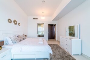 A modern bedroom with a large bed, a dresser, and a television on the wall.