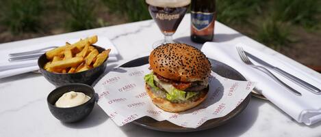 A meal consisting of a burger, fries, and a drink on a table outdoors.