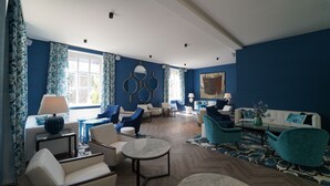 A spacious living room with a blue and white color scheme, featuring a sofa, armchairs, a coffee table, and a patterned rug. - Fletcher Hotel-Restaurant De Oude Gevangenis - Alkmaar (Alkmaar)