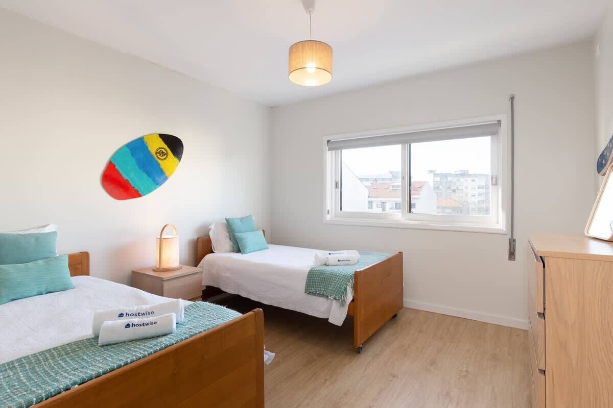 Ein Hotelzimmer mit zwei Betten, einem Fenster, einer Lampe und einer Wanddekoration.