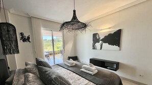 Une chambre à coucher avec un lit, une télévision, un balcon et un tableau.