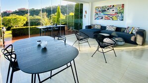 Un salon moderne avec un coin repas, de grandes portes vitrées donnant sur un jardin et un ventilateur de plafond.
