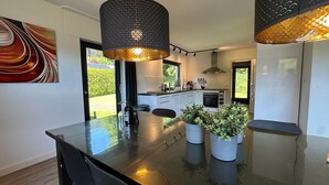 Une cuisine moderne dotée d’un îlot central, de luminaires suspendus et de plantes en pot.