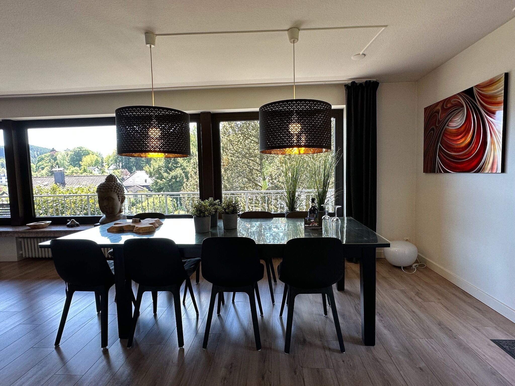 Un coin repas avec une table en verre, des chaises noires et deux lampes suspendues.