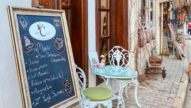 A chalkboard menu outside a cafe with a wooden door and window shutters. - Trilye Bay C Konak (Mudanya)