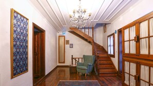 A hallway with a wooden staircase, a chandelier, a patterned wall, and a green armchair. - Trilye Bay C Konak (Mudanya)
