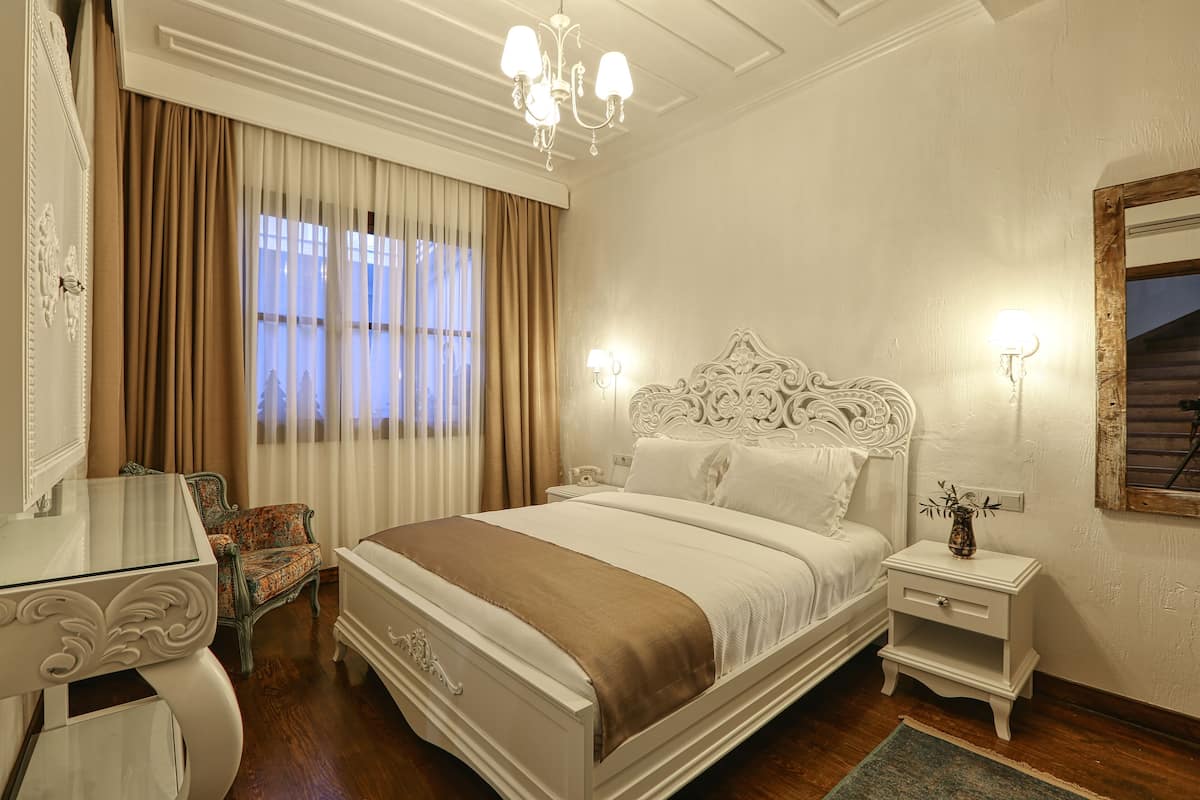 A bedroom with a large bed, a nightstand, a dresser, and a chair.