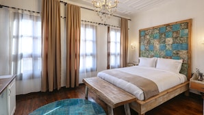 A bedroom with a large bed, wooden headboard, and a chandelier. - Trilye Bay C Konak (Mudanya)