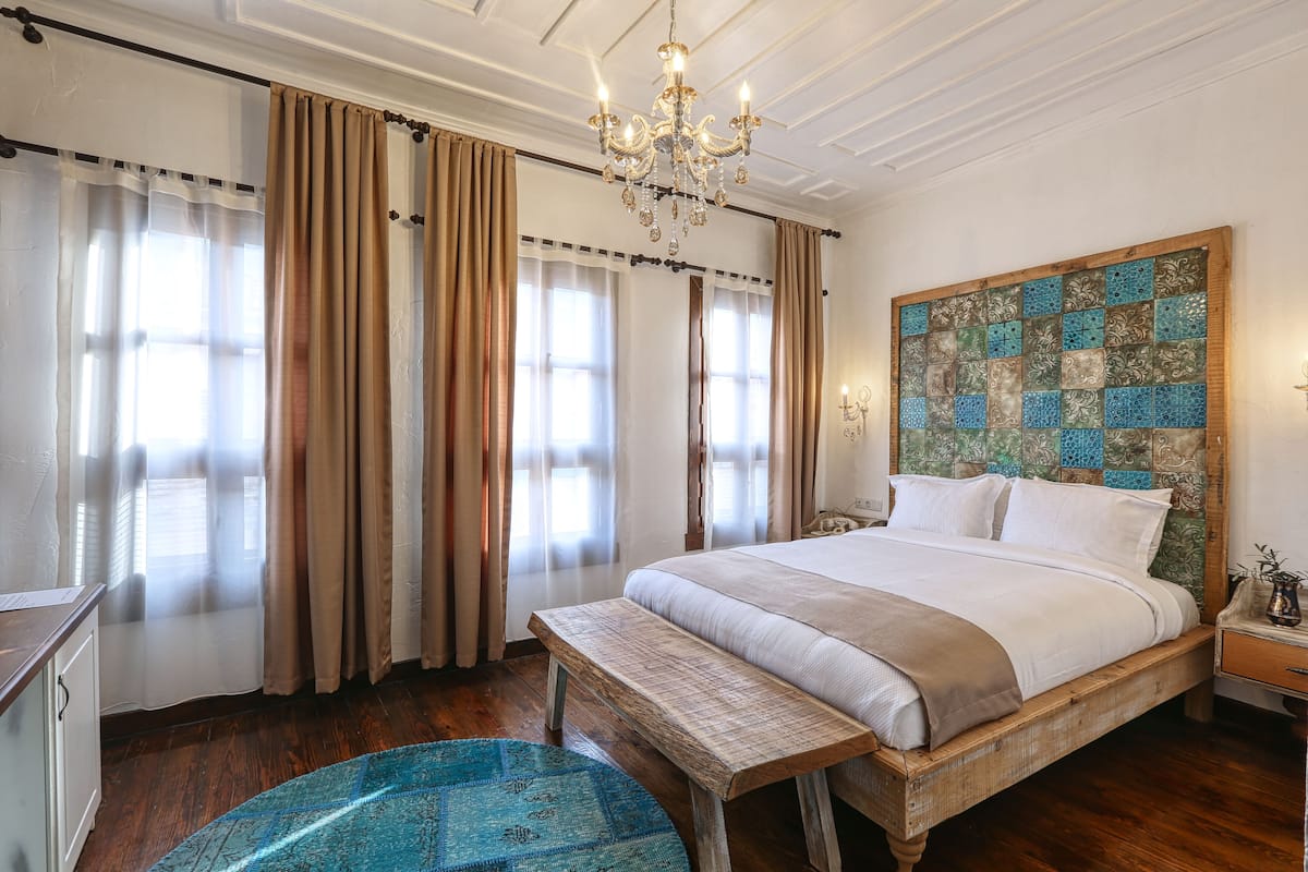 A bedroom with a large bed, wooden headboard, and a chandelier.