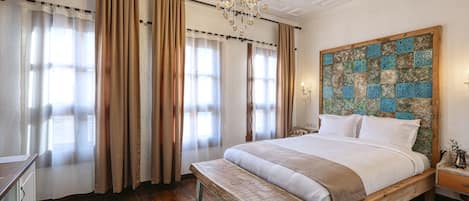 A bedroom with a large bed, wooden headboard, and a chandelier.