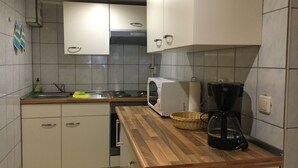 A kitchen with white cabinets, a wooden countertop, a microwave, a coffee maker, and a sink. - Ferienwohnung Reifberg (Ilmenau)