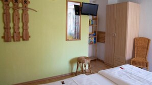 A room with a bed, a wardrobe, a television, a mirror, and a small stool. - Ferienwohnung Reifberg (Ilmenau)