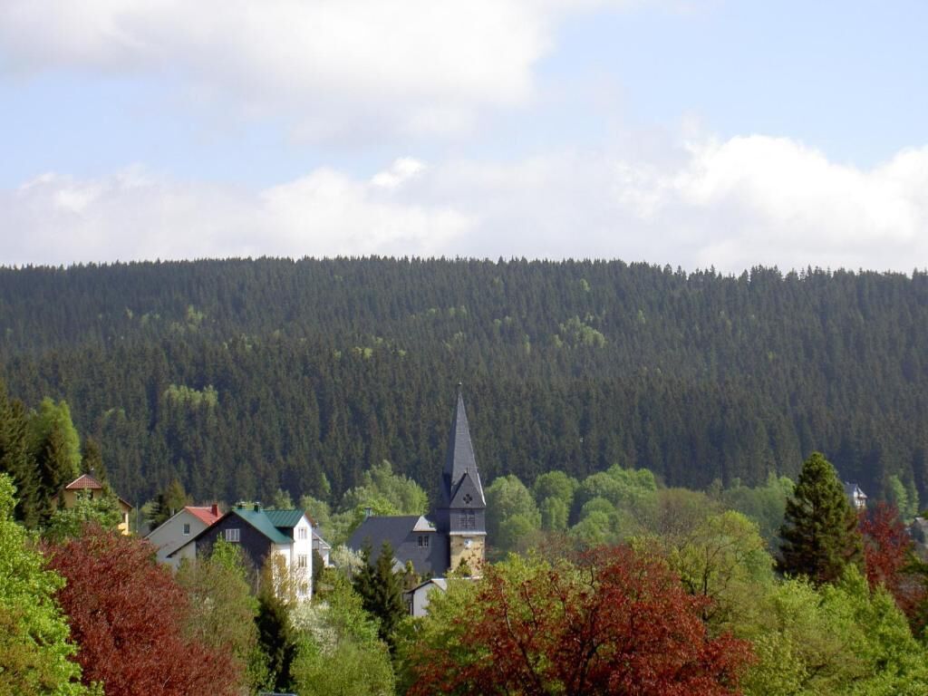 A church with a pointed steeple surrounded by trees and houses.