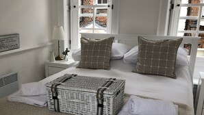 A neatly made bed with a white headboard, two pillows, a wicker basket, and folded towels on a beige bedspread. - * SEE OVER 170 AMAZING GUEST REVIEWS ON AIRBNB * Location * Location * Location (Poole)