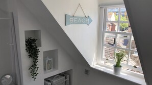 A room with a sloped ceiling, a window with a view of buildings, a wall-mounted sign reading "BEACH", and a small plant on the windowsill. - * SEE OVER 170 AMAZING GUEST REVIEWS ON AIRBNB * Location * Location * Location (Poole)