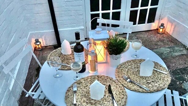 A round outdoor dining table with white chairs, set with woven placemats, cutlery, and glassware. - * SEE OVER 170 AMAZING GUEST REVIEWS ON AIRBNB * Location * Location * Location (Poole)