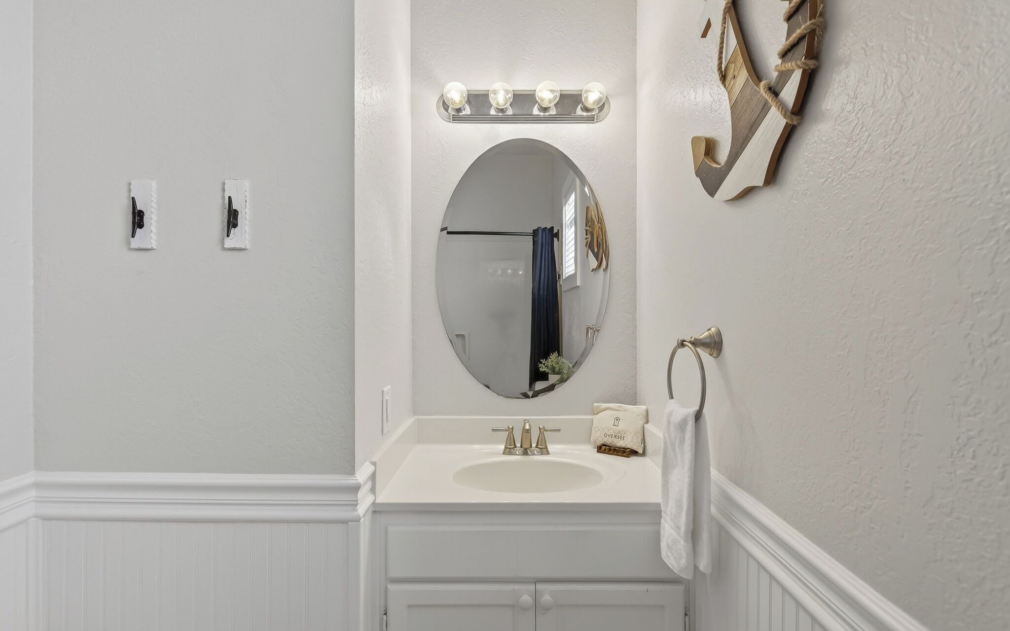 A bathroom with a white vanity, a round mirror, and a lighted vanity mirror.