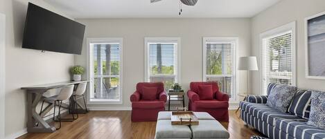 Una sala de estar con ventilador de techo, televisor y sofá.