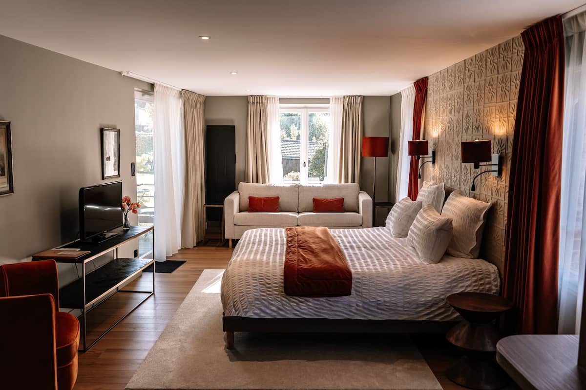 A modern bedroom with a large bed, a TV, a sofa, and a desk.