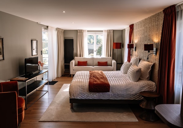 Un dormitorio moderno con una cama grande, un televisor, un sofá y un escritorio.