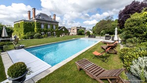 A swimming pool with lounge chairs and a wooden deck.