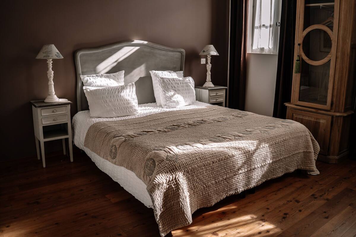 A neatly made bed with a textured blanket, two bedside tables with lamps, and a wooden cabinet.