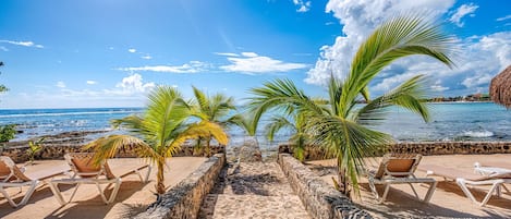 Un salón junto a la playa con paredes de piedra y sillones.