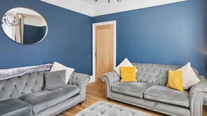 A living room with two grey upholstered sofas, a round mirror, and a wooden door. - Host & Stay | Simba House (Saltburn-by-the-Sea)