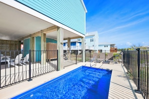 A swimming pool with a wooden deck, a covered patio area, and a view of neighboring houses. - Gulf Views | Pet Friendly | Private Pool | Beach Access (Fort Morgan)
