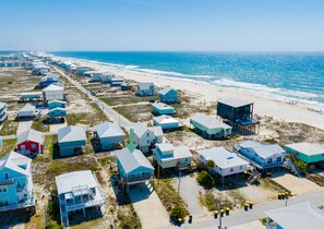 A coastal area with beachfront properties, including houses and a beach house with a balcony.