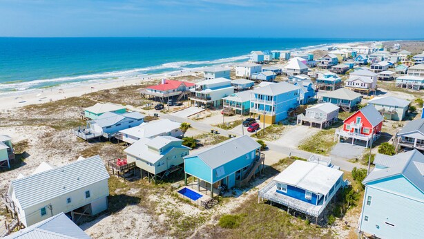 A coastal residential area with houses, a beach, and the ocean.