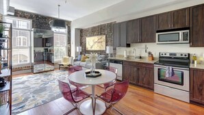 A modern kitchen with dark wood cabinets, stainless steel appliances, and a round glass table with chairs. - The Loft on Broughton, Modern | Stylish | Chic (Savannah)