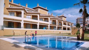 Un hotel con piscina, varios balcones y cielo despejado.