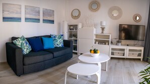 A modern living room with a dark grey sofa, white coffee table, and a flat-screen TV on a white stand. - APARTMENT SEEVIEW ON THE BEACH PARKING ALL INCLUSIVE TORROX NERJA MALAGA SPAIN (Torrox Costa)