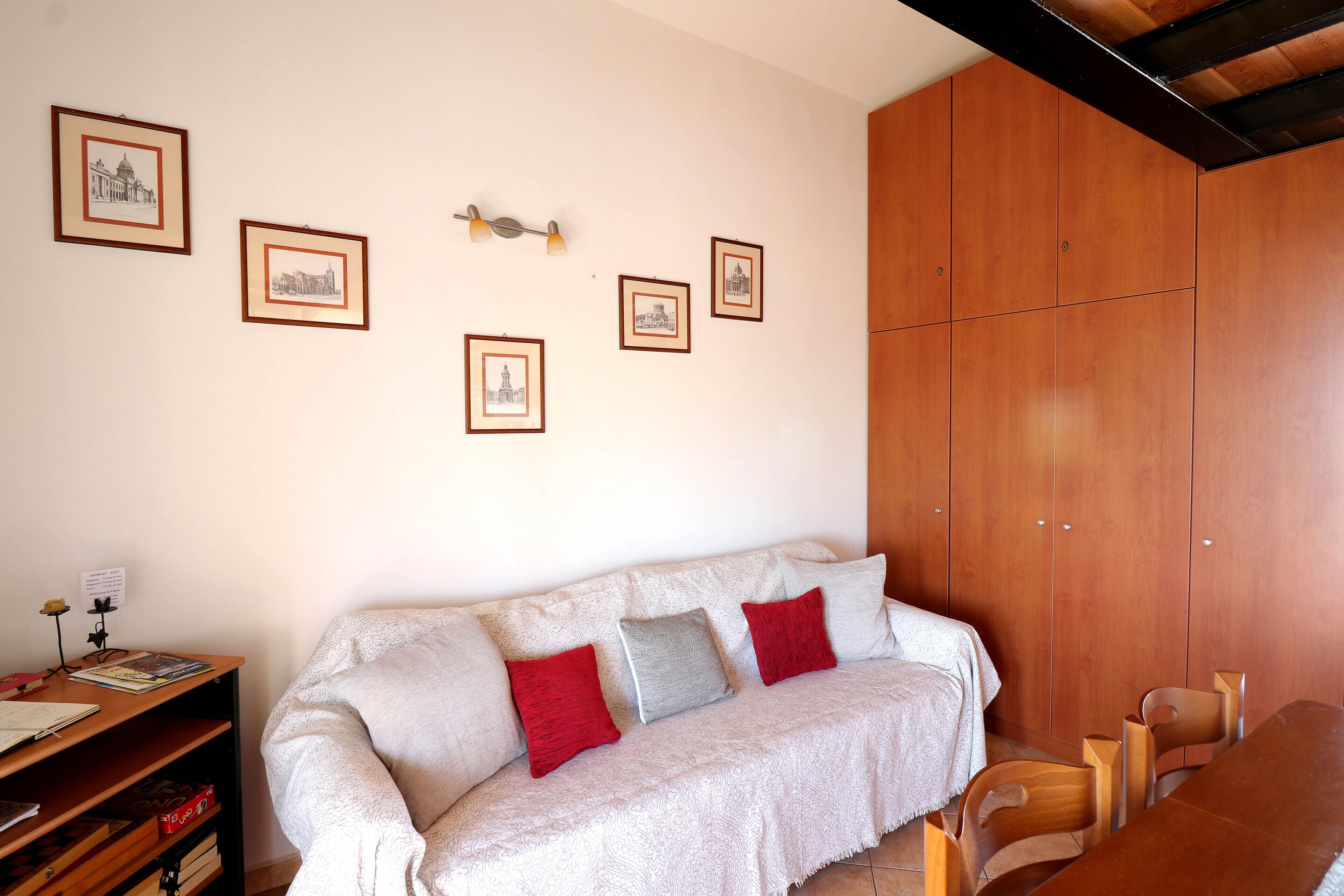 Una habitación con sofá, armario de madera y cuadros en la pared.
